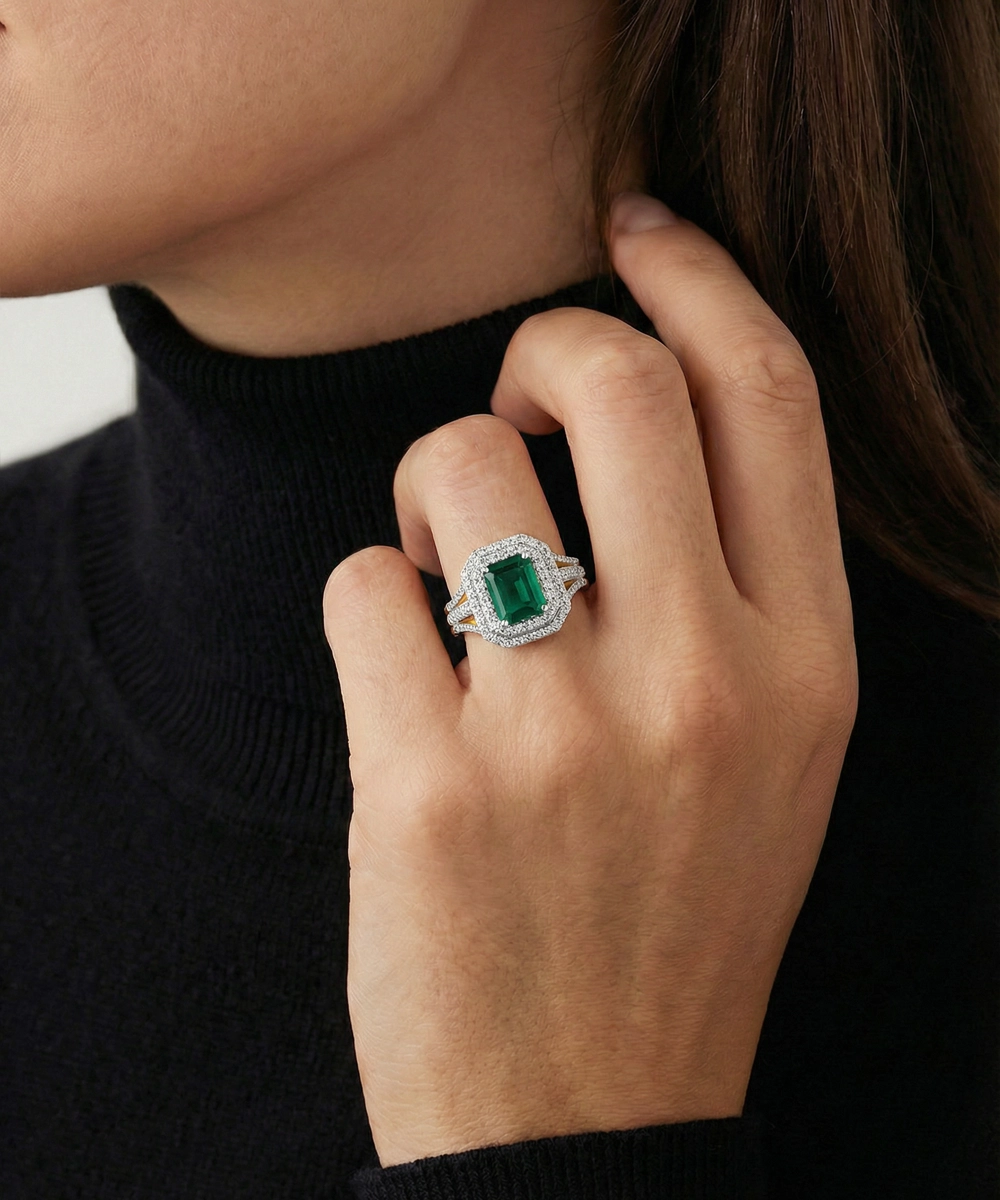 Close-up of a hand wearing an emerald-cut ring with a black background