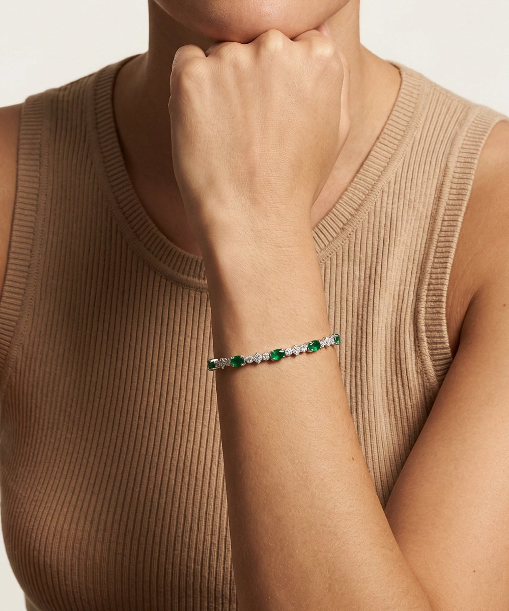 Person wearing a bracelet with green and clear stones on a neutral background