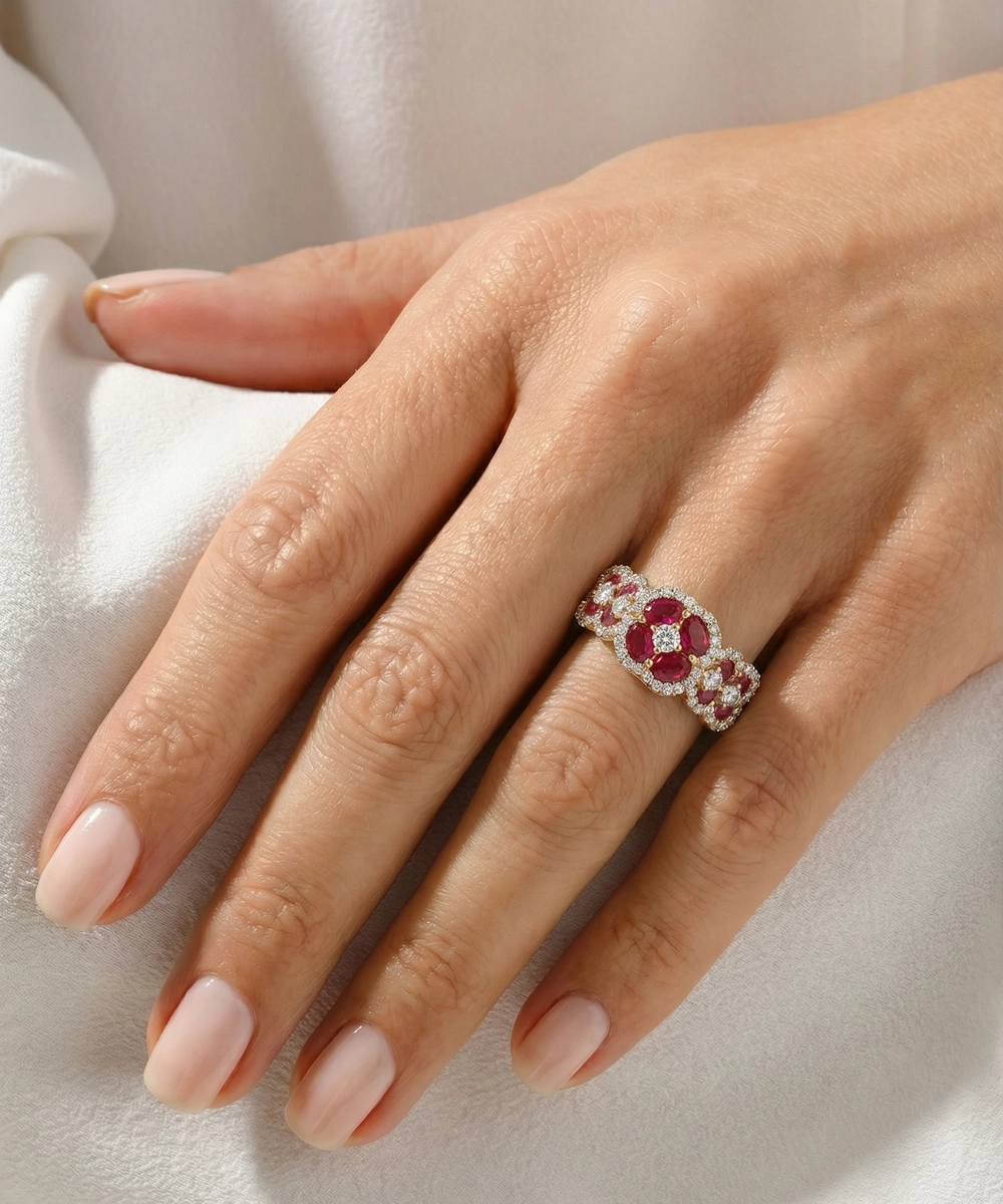 Hand wearing a ring with red gemstones on a light fabric background