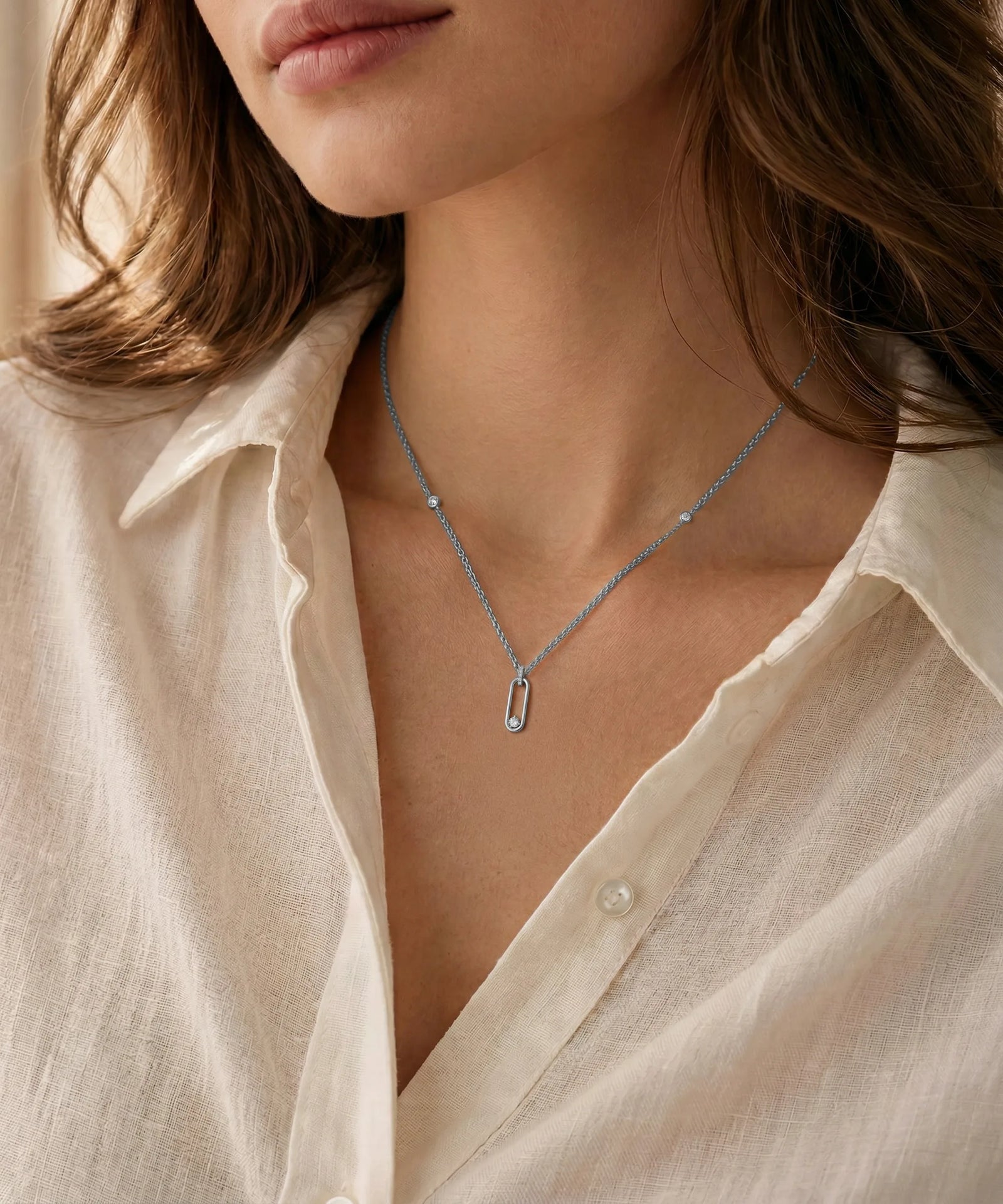 Close-up of a person wearing a delicate silver necklace with a minimalistic pendant.