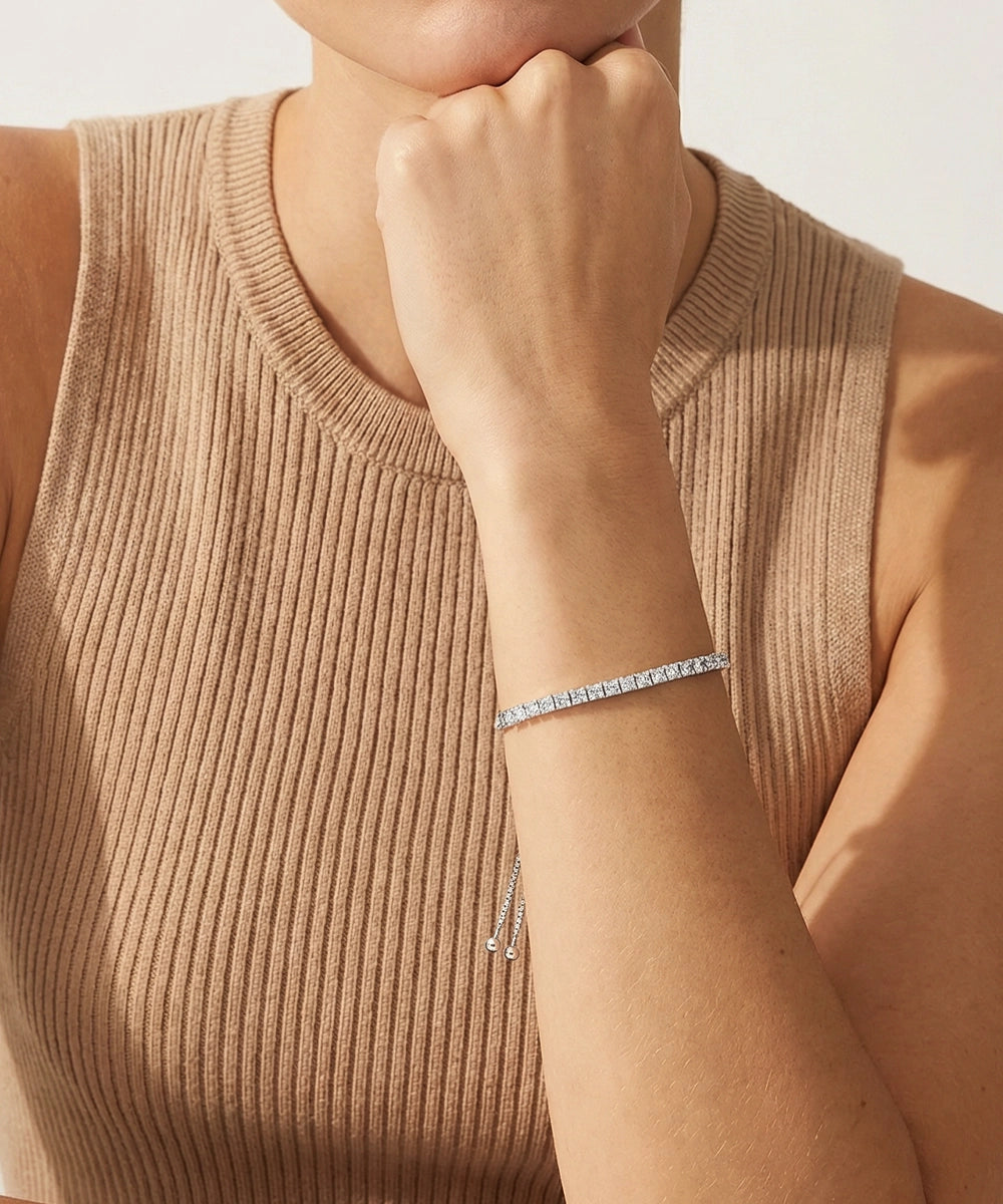 Person wearing a delicate bracelet on a neutral background