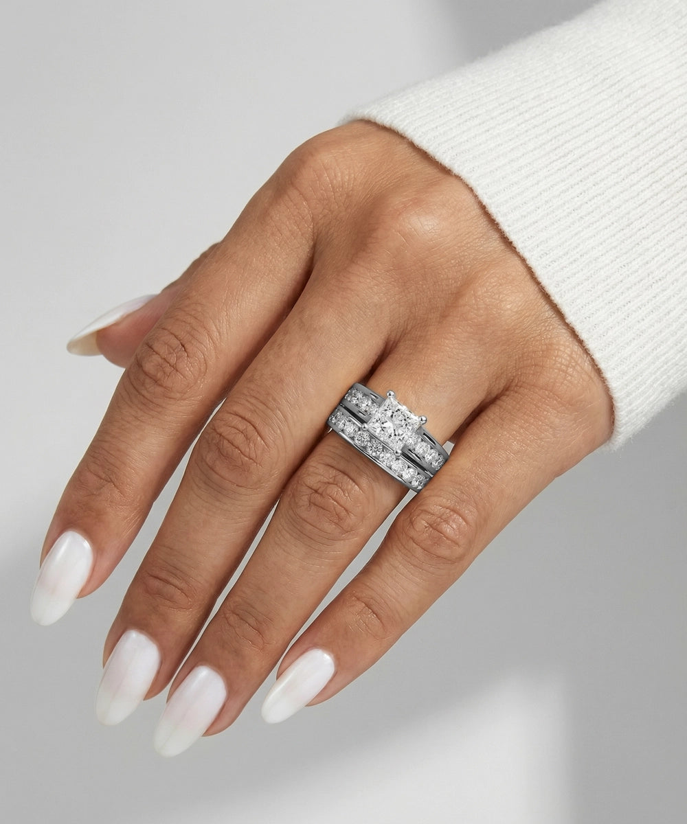 Hand wearing a silver ring with a diamond on a neutral background