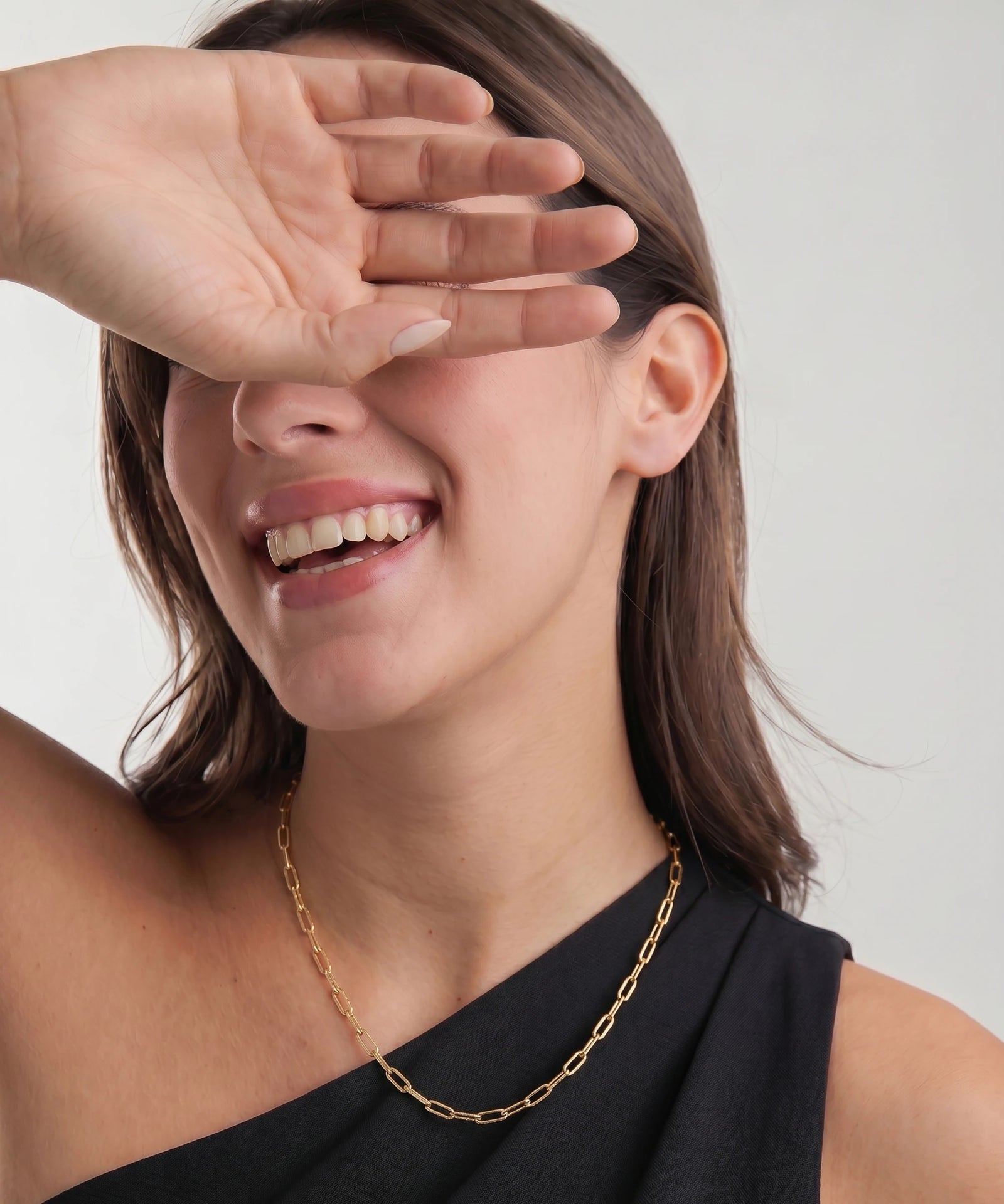 Woman wearing a gold chain necklace with a plain background