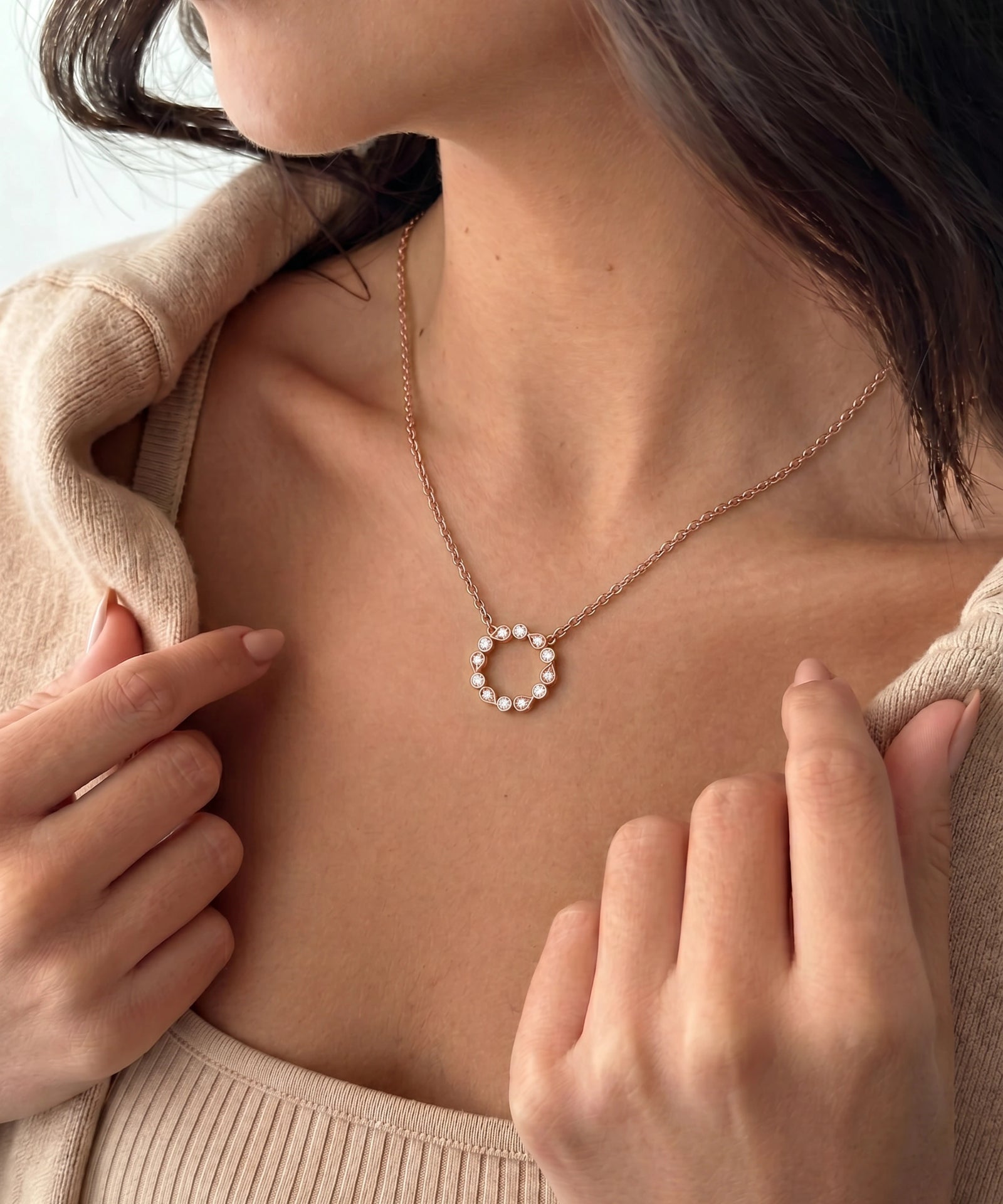 A close-up of a woman wearing a delicate gold chain necklace with a butterfly pendant. The butterfly is detailed with small pink and red gemstones.