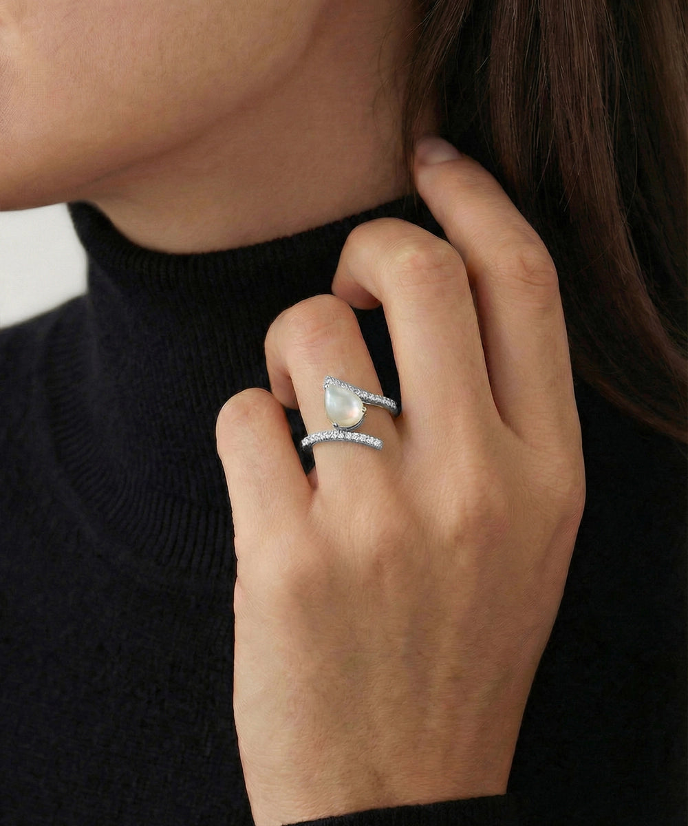 Close-up of a hand wearing two silver rings with a black background