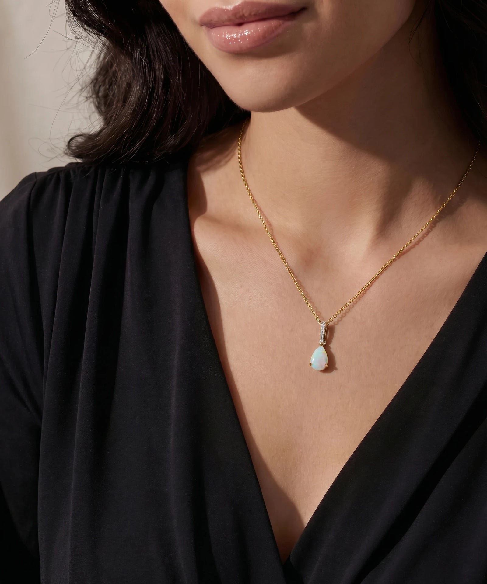 Close-up of a woman wearing a gold necklace with a pendant.