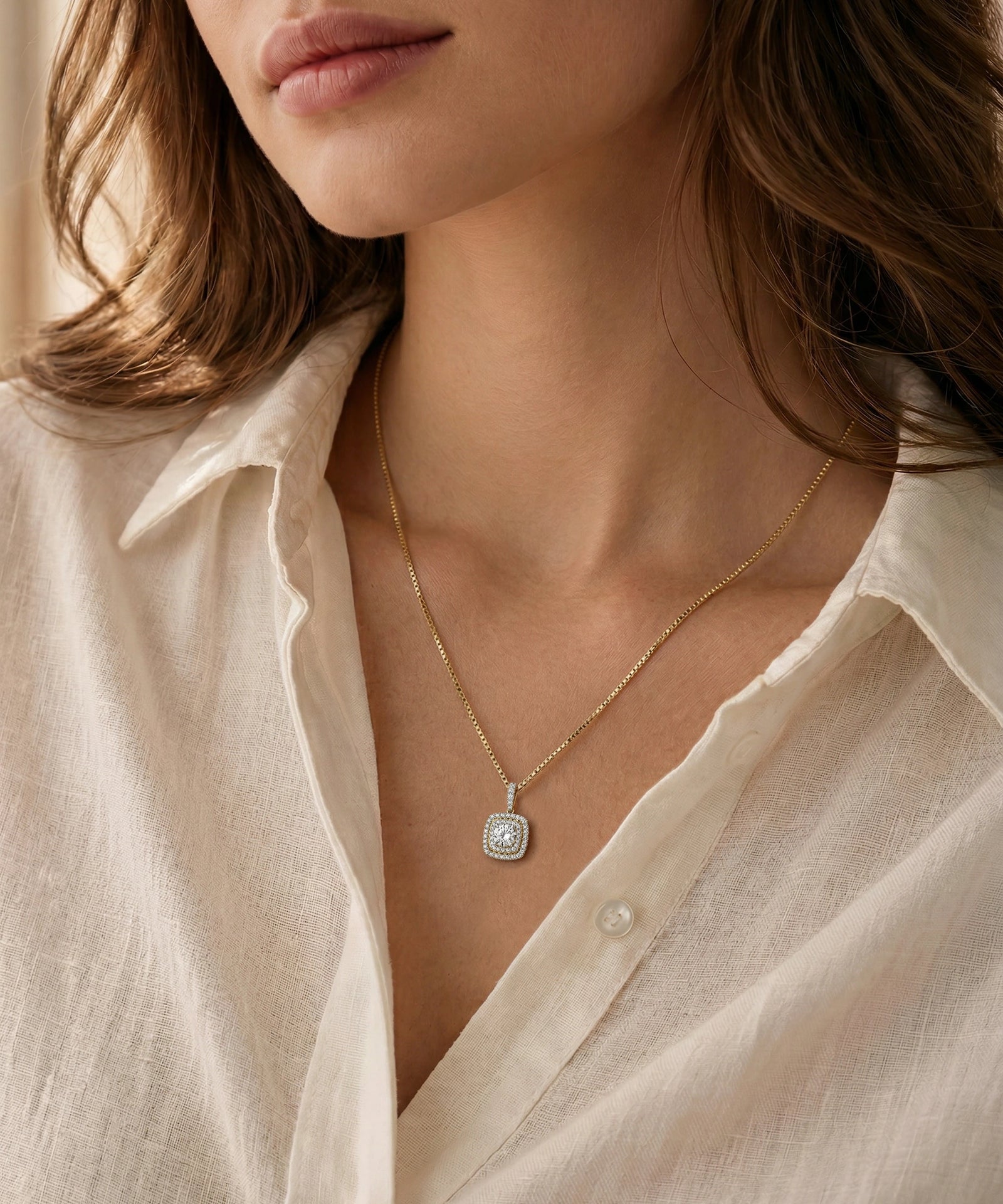 Close-up of a person wearing a delicate gold necklace with a pendant.
