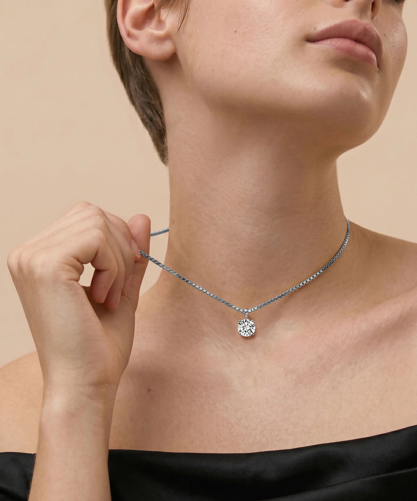 Necklace with a pendant being worn by a person against a neutral background