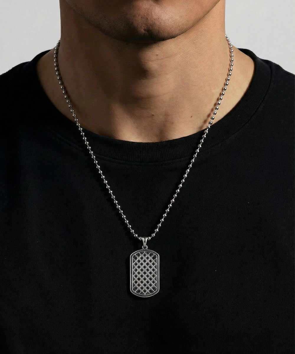 Silver chain necklace with a dog tag on a person wearing a black shirt.