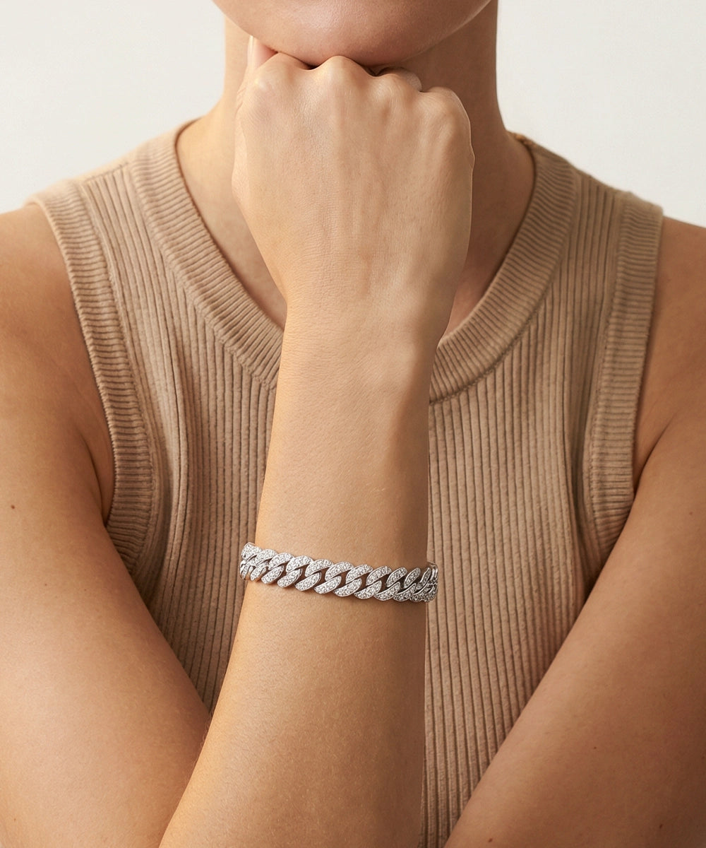Person wearing a silver bracelet on a neutral background