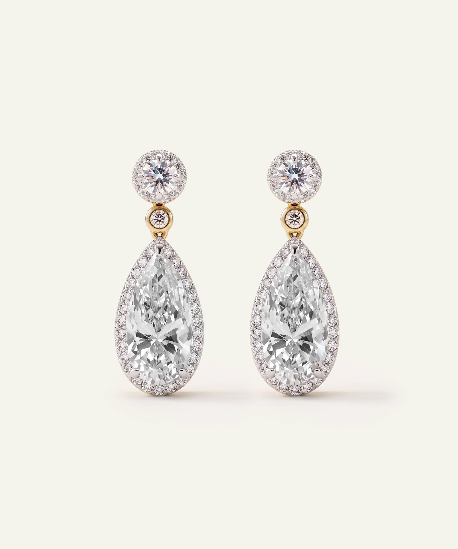Pair of pear-cut diamond drop earrings with halo settings in white and yellow gold.