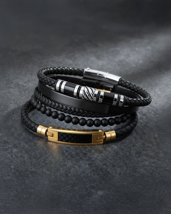 Stack of black leather and beaded bracelets with metal clasps on a dark gray background