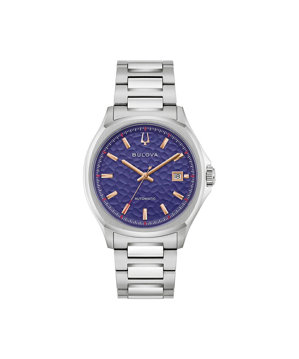 A Bulova watch with a stainless steel link bracelet and a textured blue dial, featuring gold-tone hands and hour markers, shown against a plain white background.