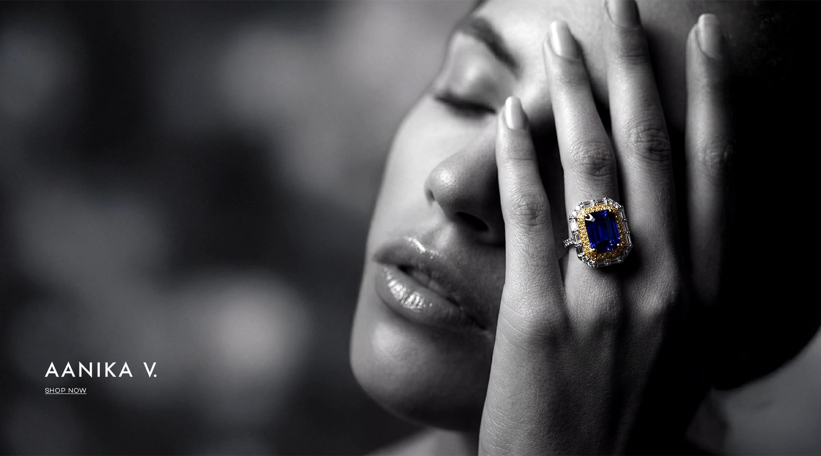 Close-up of a woman's face with a ring on her finger, blurred background