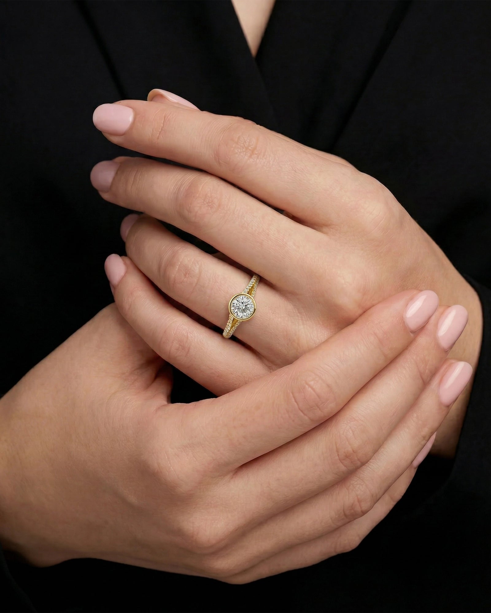 Close-up of a hand wearing a gold ring with a diamond on a black background