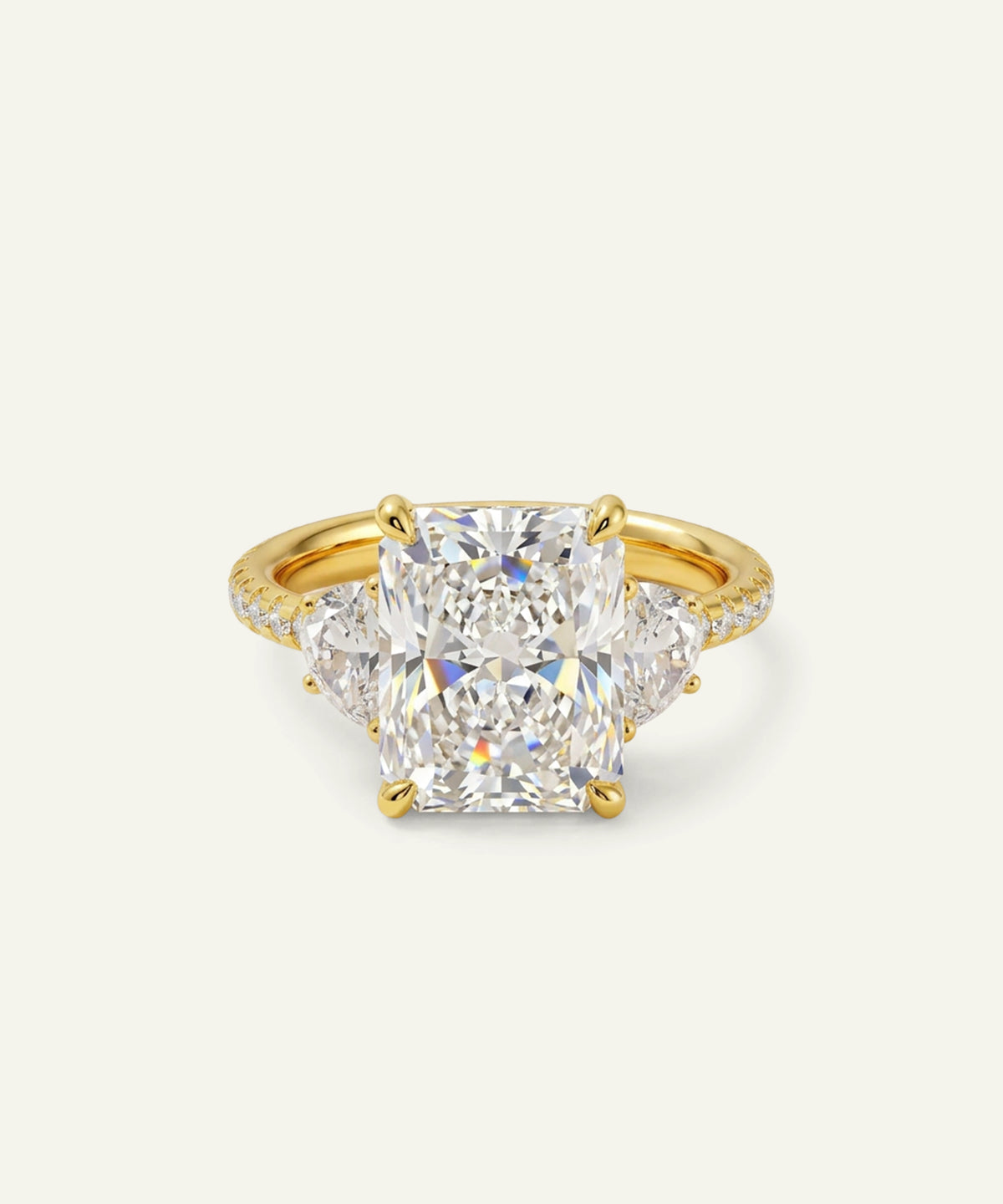 A yellow gold ring featuring a large cushion-cut diamond center stone with two smaller round diamonds on either side, set against a plain off-white background.