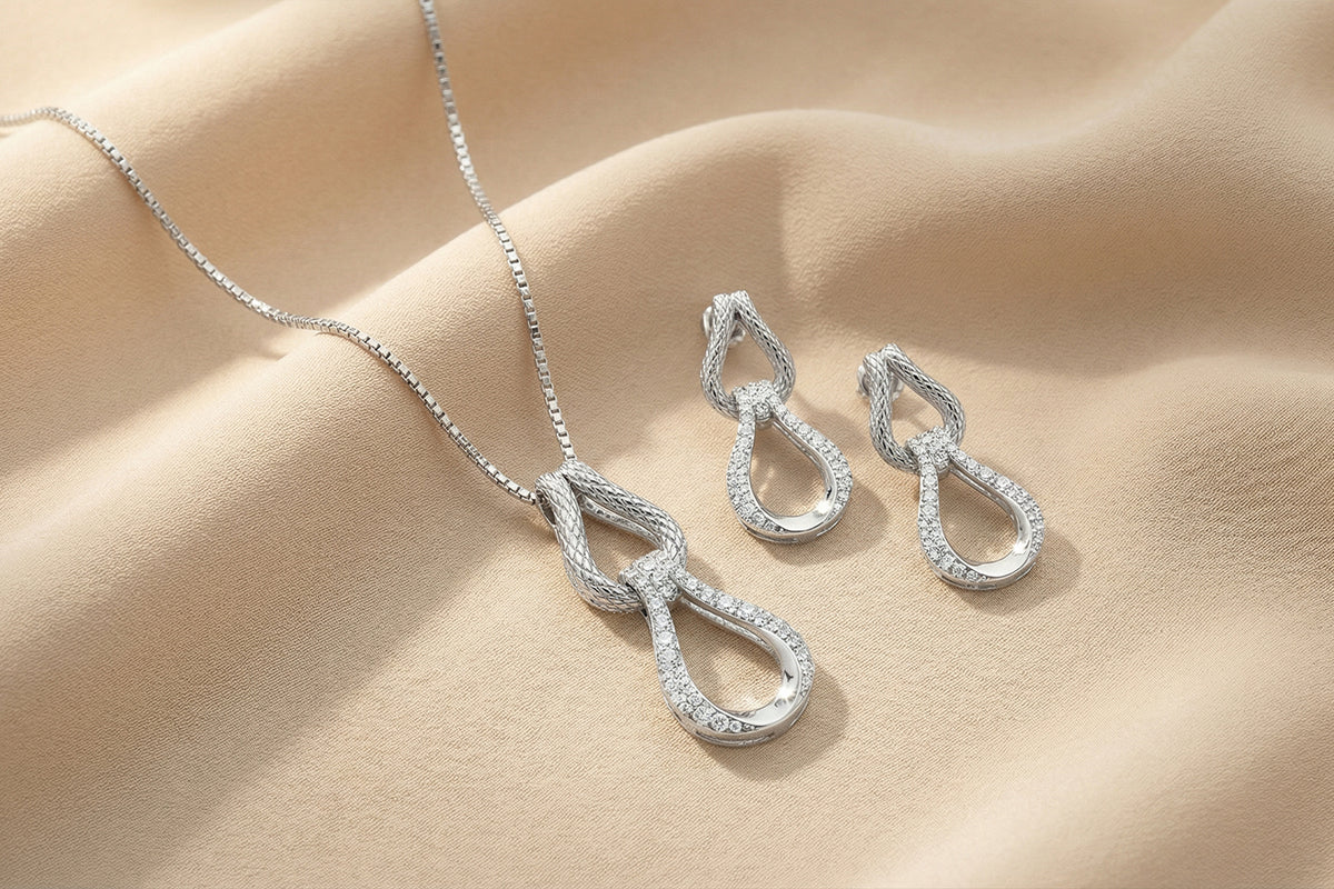 Silver necklace and earrings on a beige fabric background