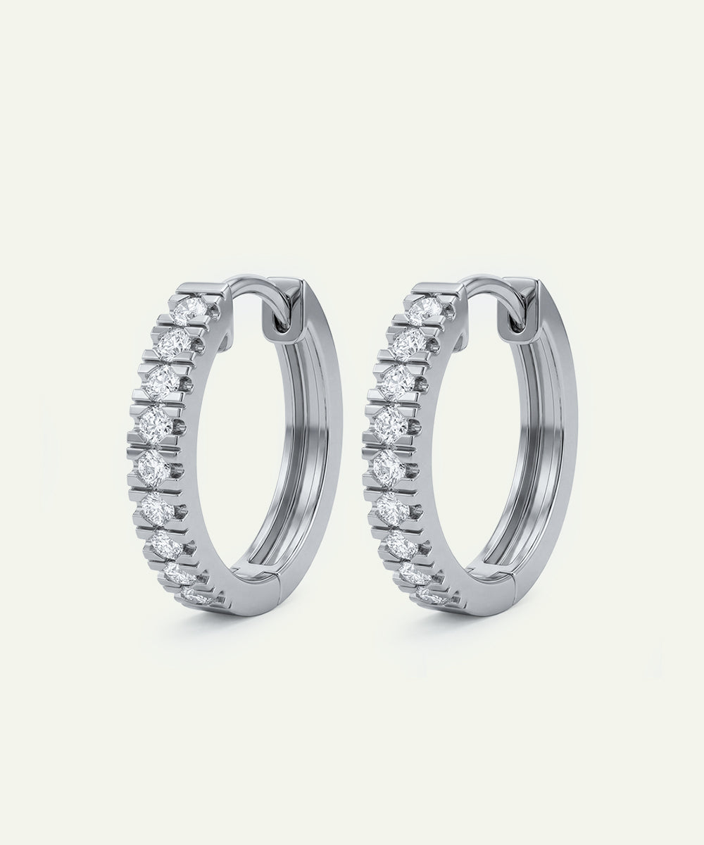 Pair of silver hoop earrings with clear gemstones on a white background