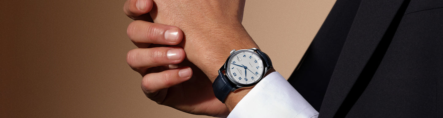 Close-up of a person wearing a watch with a neutral background