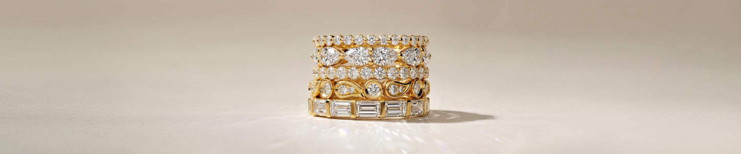 Stack of gold and diamond rings on a beige background
