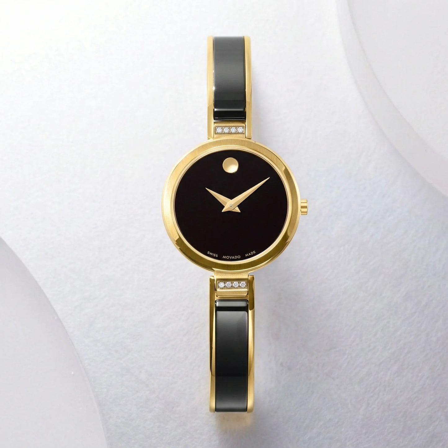 Women's Movado gold bangle watch with a minimalist black dial and diamond accents.