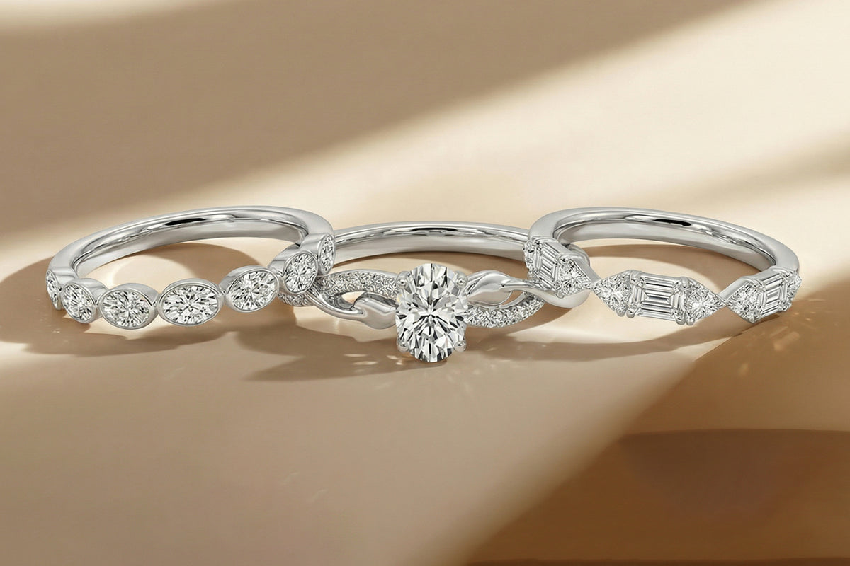 Three elegant diamond rings are displayed on a beige surface, each featuring a unique arrangement of sparkling diamonds set in silver bands with soft natural light casting gentle shadows.