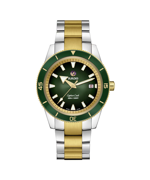 Two-tone silver and gold watch with green bezel and black face on a white background