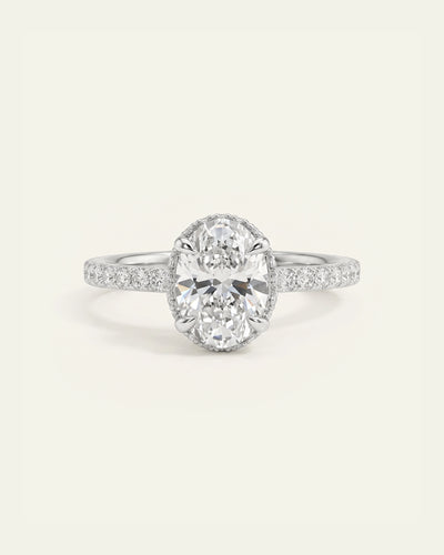 White gold oval-cut diamond engagement ring with a pavé band.