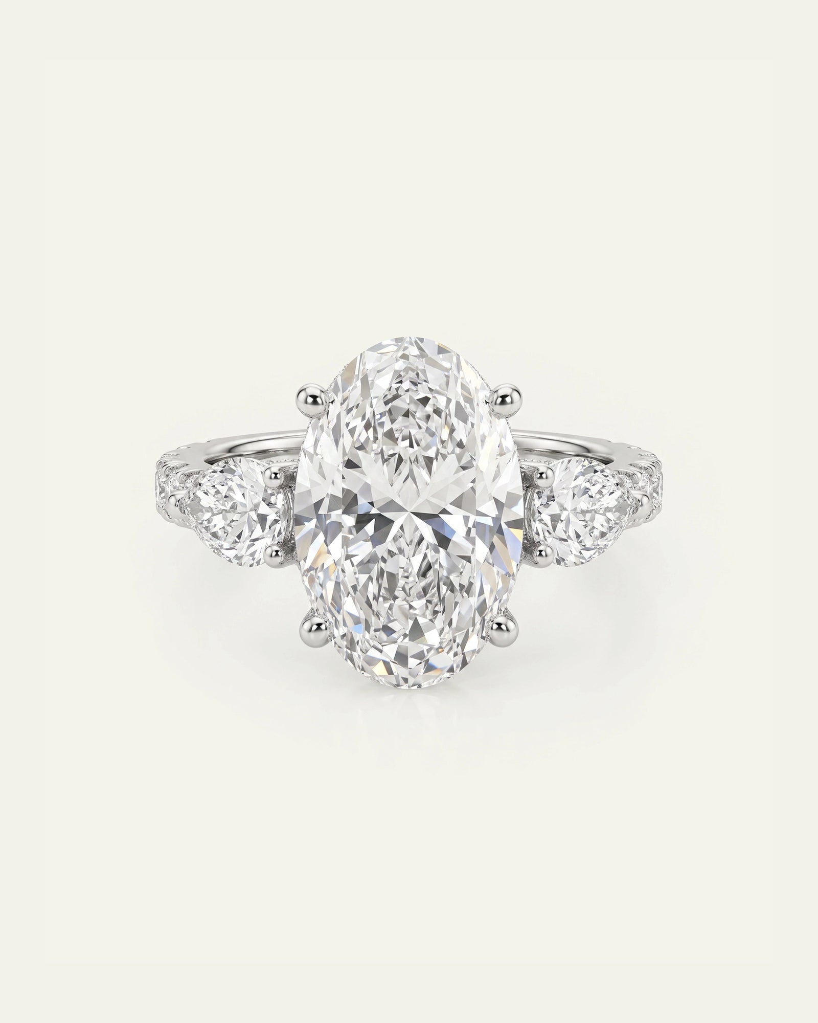 An oval diamond engagement ring with a three-stone setting, featuring a large oval center stone and smaller round diamonds on the shoulders, set against a light cream background.