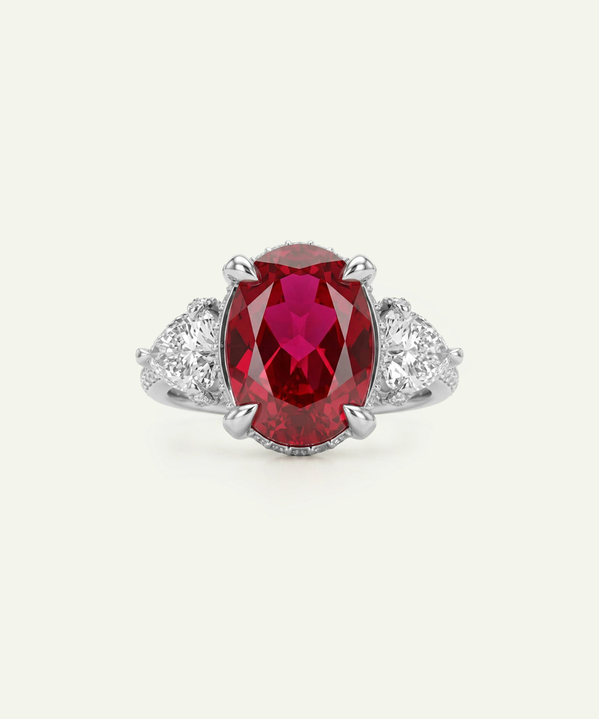 An oval-cut red gemstone ring with a silver-toned setting and small clear accent stones on either side, centered on a light cream background.