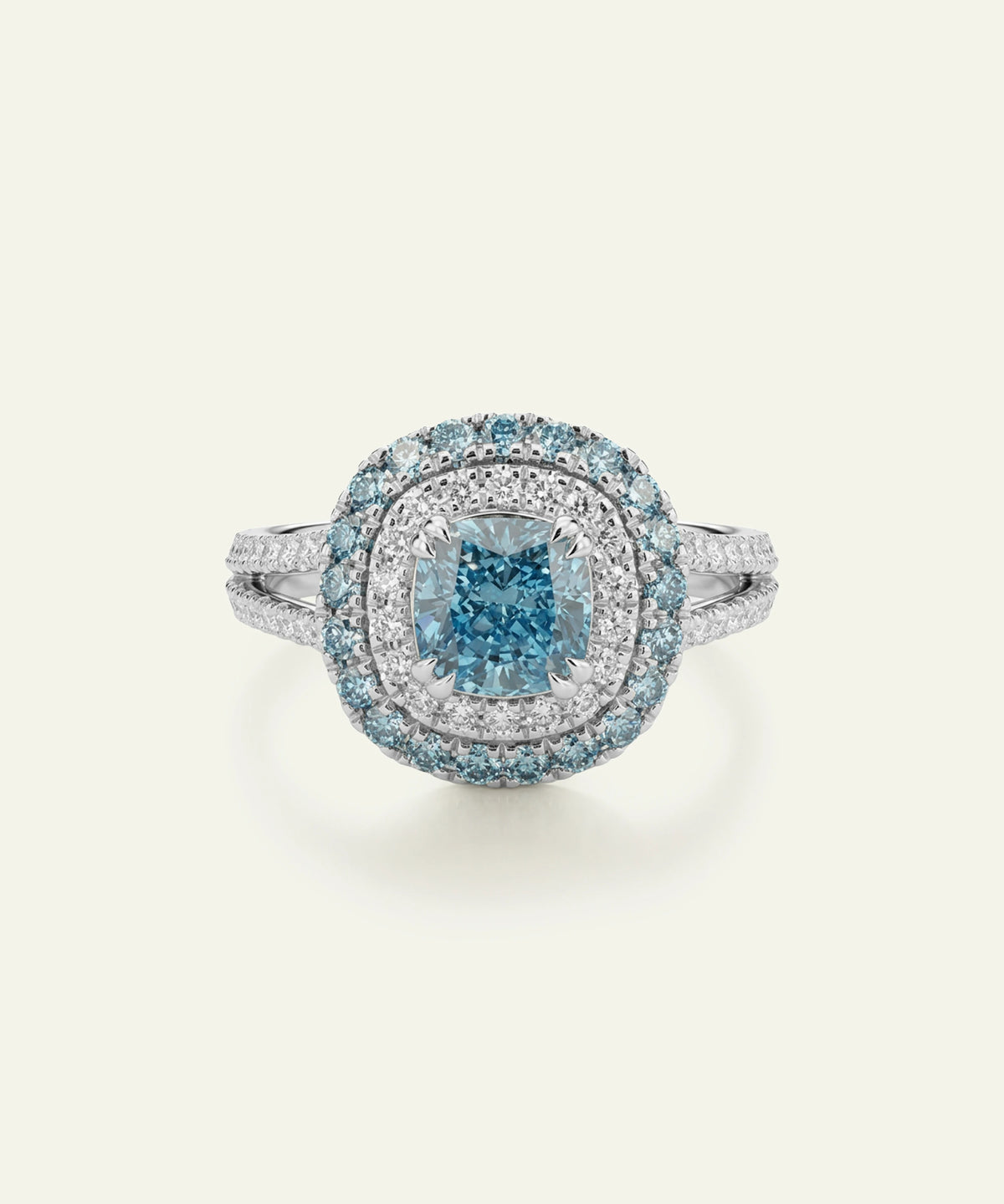 A round halo ring featuring a central cushion-cut light blue gemstone surrounded by a double halo of small clear stones, set on a silver-toned band against a light cream background.