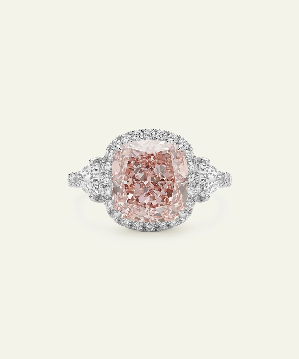 A silver ring featuring a large cushion-cut pink diamond center stone with a diamond halo, flanked by triangular or shield-cut side diamonds and a pavé diamond band, set against a light cream background.