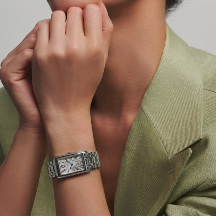 Person wearing a silver watch on a light background