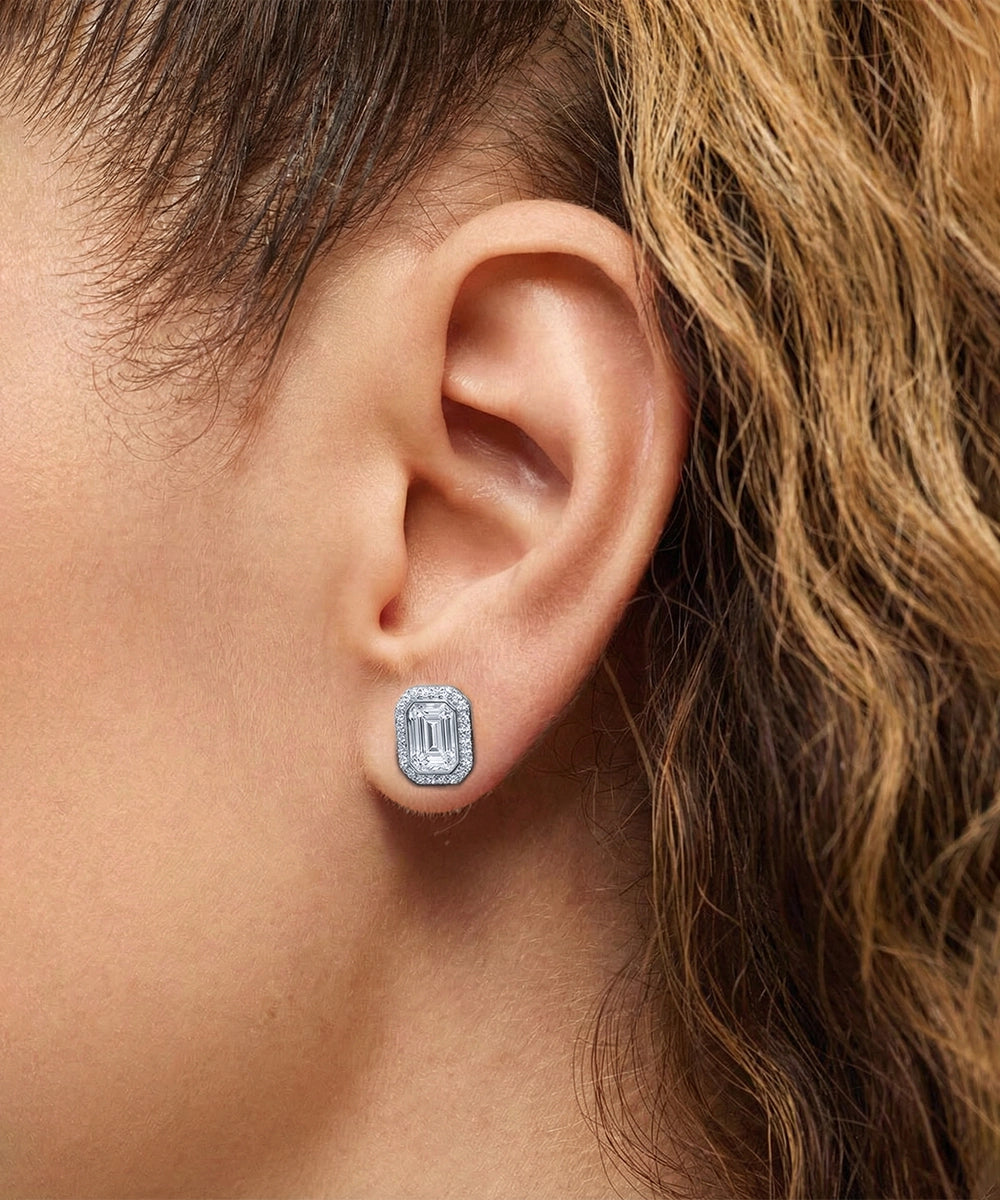 Close-up of an ear wearing a diamond stud earring with hair partially covering the frame.