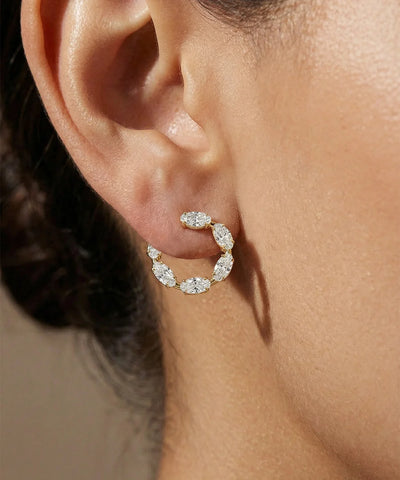 Close-up of a person wearing a diamond hoop earring with a neutral background - alternate view
