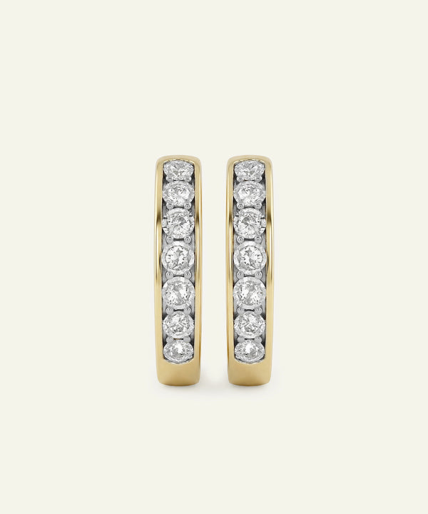 Pair of gold hoop earrings with embedded diamonds on a light gray background