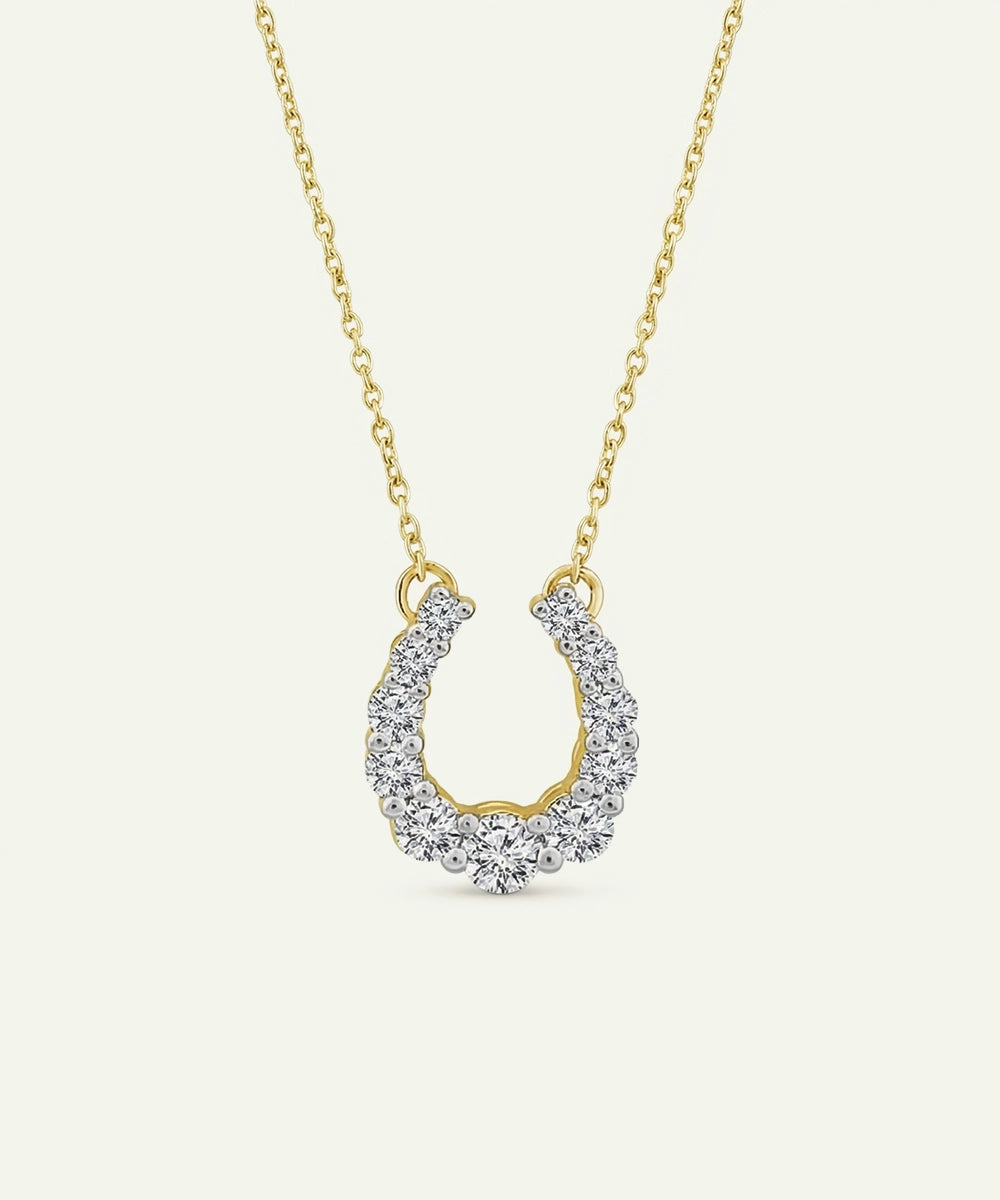 Gold necklace with a horseshoe-shaped pendant on a white background