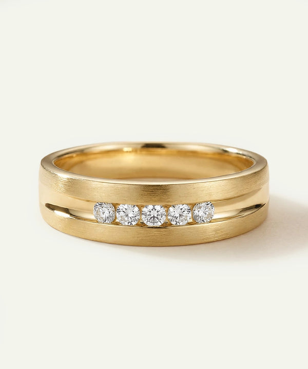 Gold ring with embedded diamonds on a light beige background