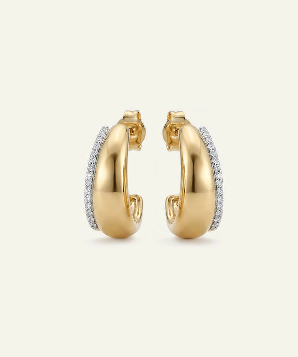 Gold hoop earrings with embedded diamonds on a light beige background
