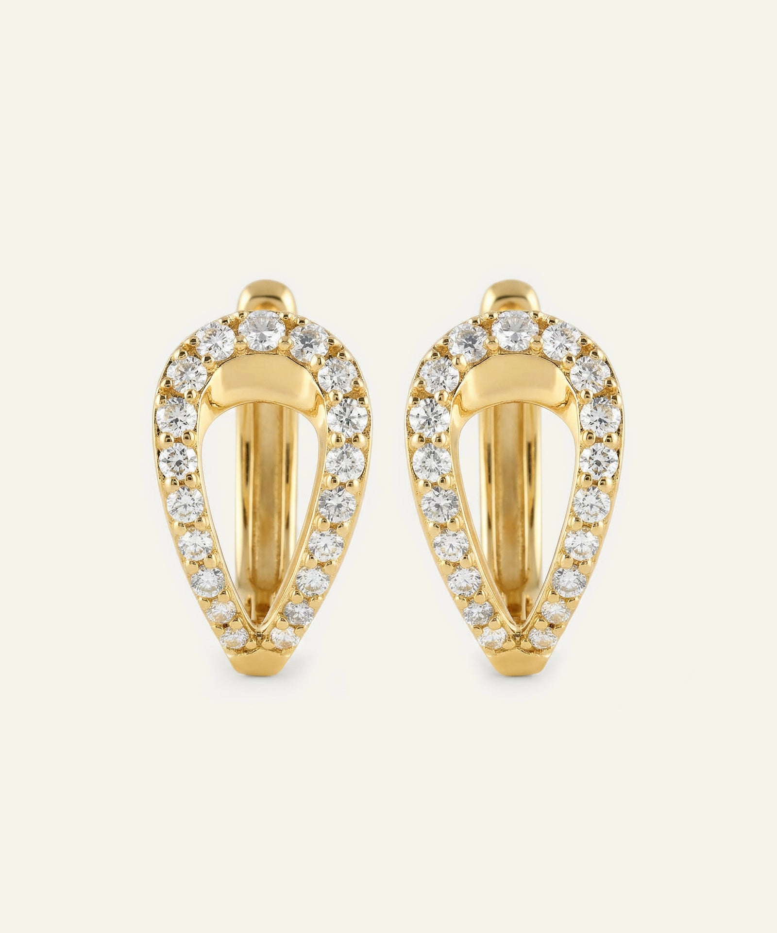 Gold hoop earrings with diamond accents on a light beige background