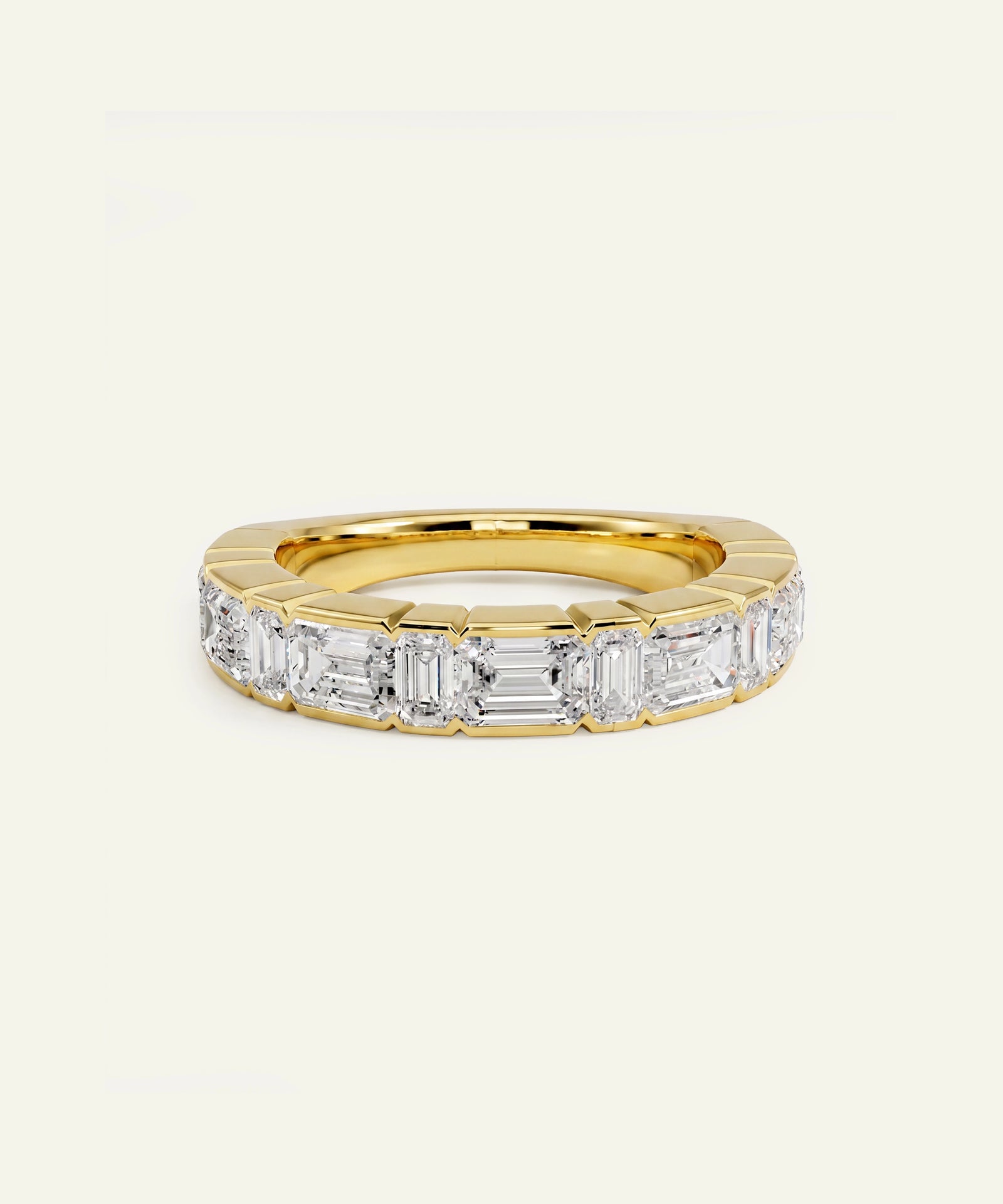 A yellow gold eternity ring featuring a row of baguette-cut clear diamonds, set against a plain off-white background.