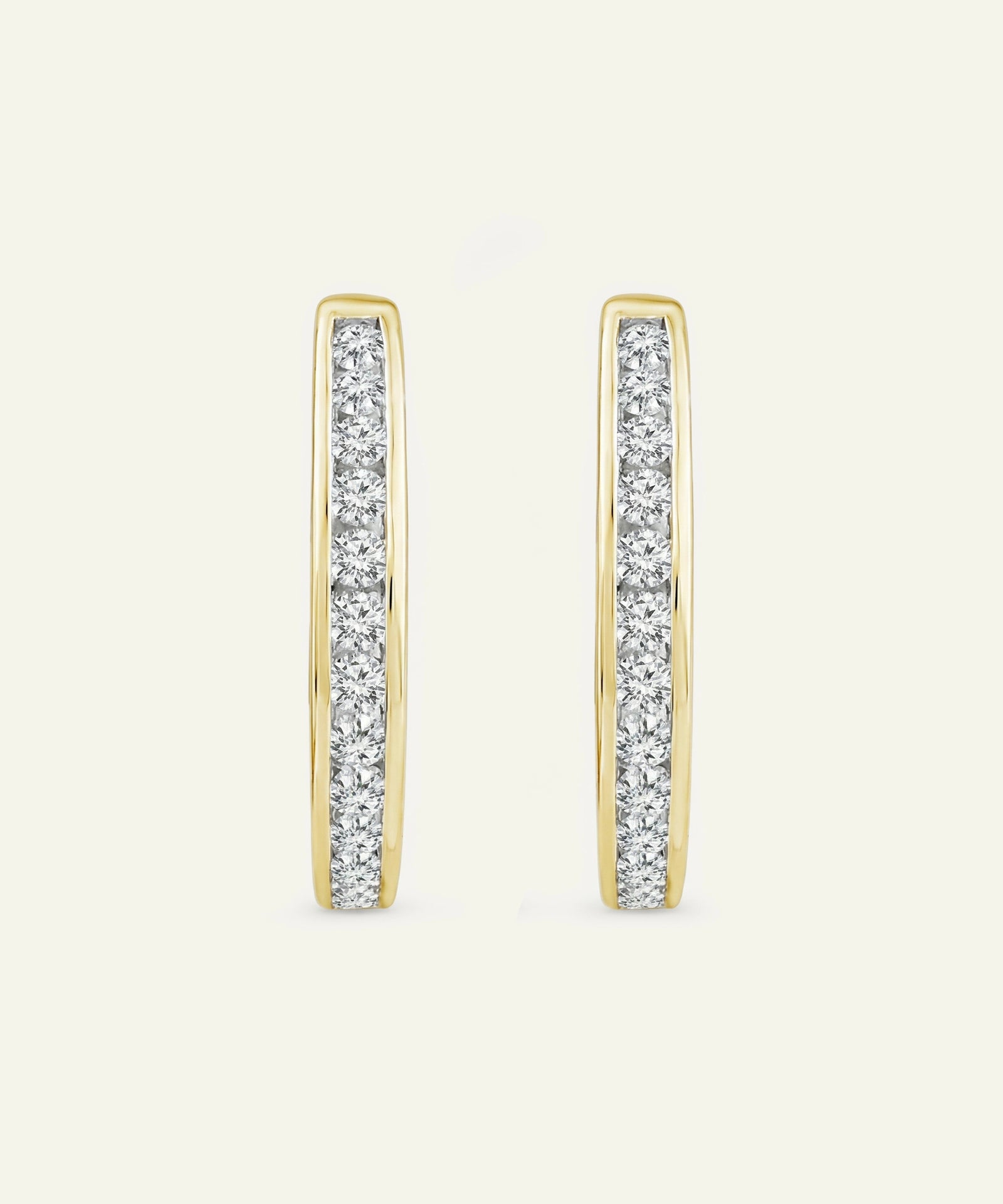 Gold hoop earrings with embedded diamonds on a light beige background