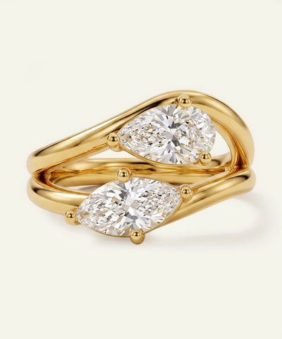 Gold ring with two diamonds on a light beige background