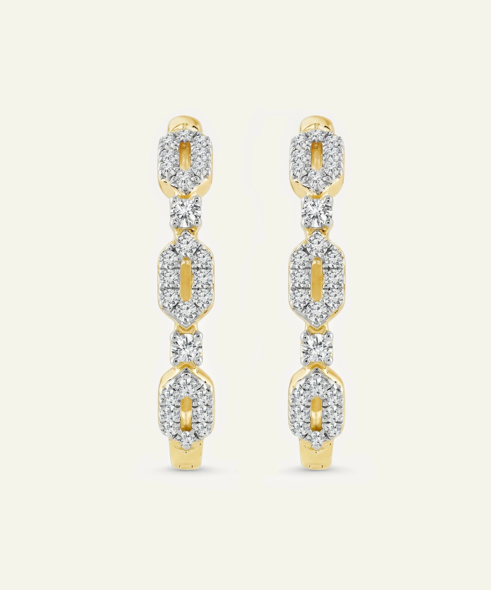 Gold and diamond earrings on a light beige background