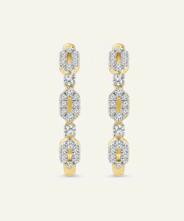 Gold and diamond earrings on a light beige background