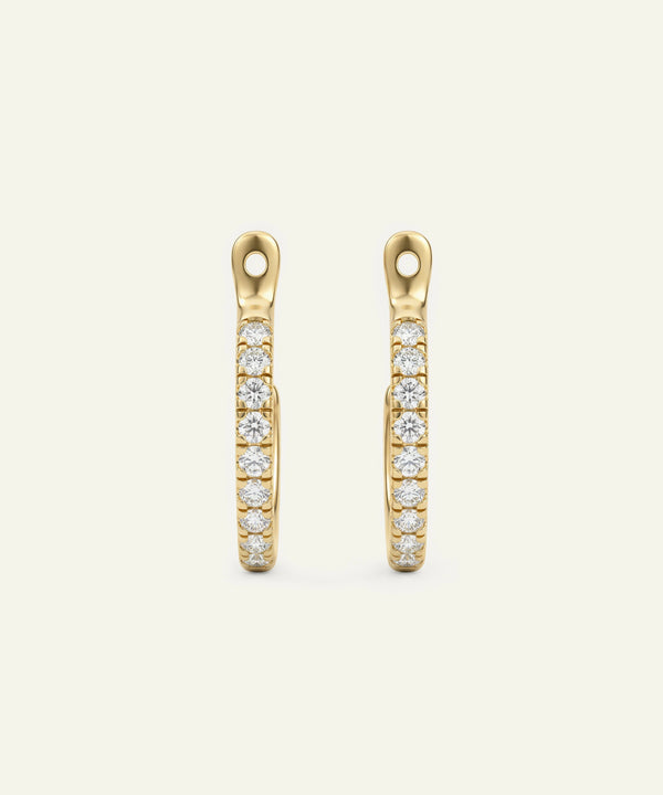 Gold earrings with embedded diamonds on a beige background