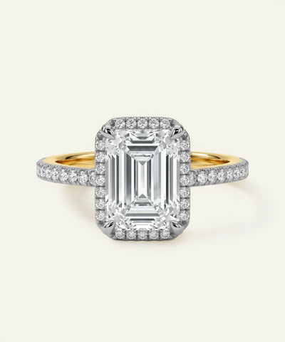 Emerald cut diamond halo engagement ring with pavé diamond band in yellow gold and platinum.