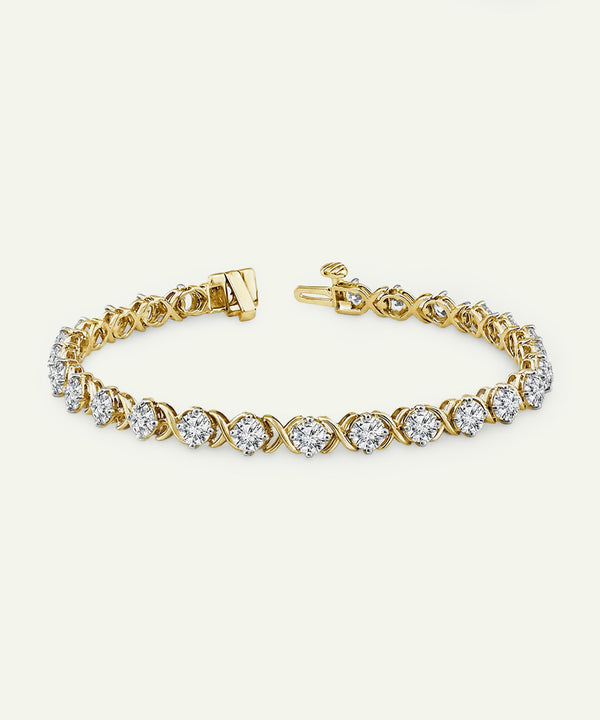 Yellow gold diamond tennis bracelet featuring an alternating pattern of prong-set round brilliant cut diamonds and polished gold X-shaped links, with a secure box clasp.