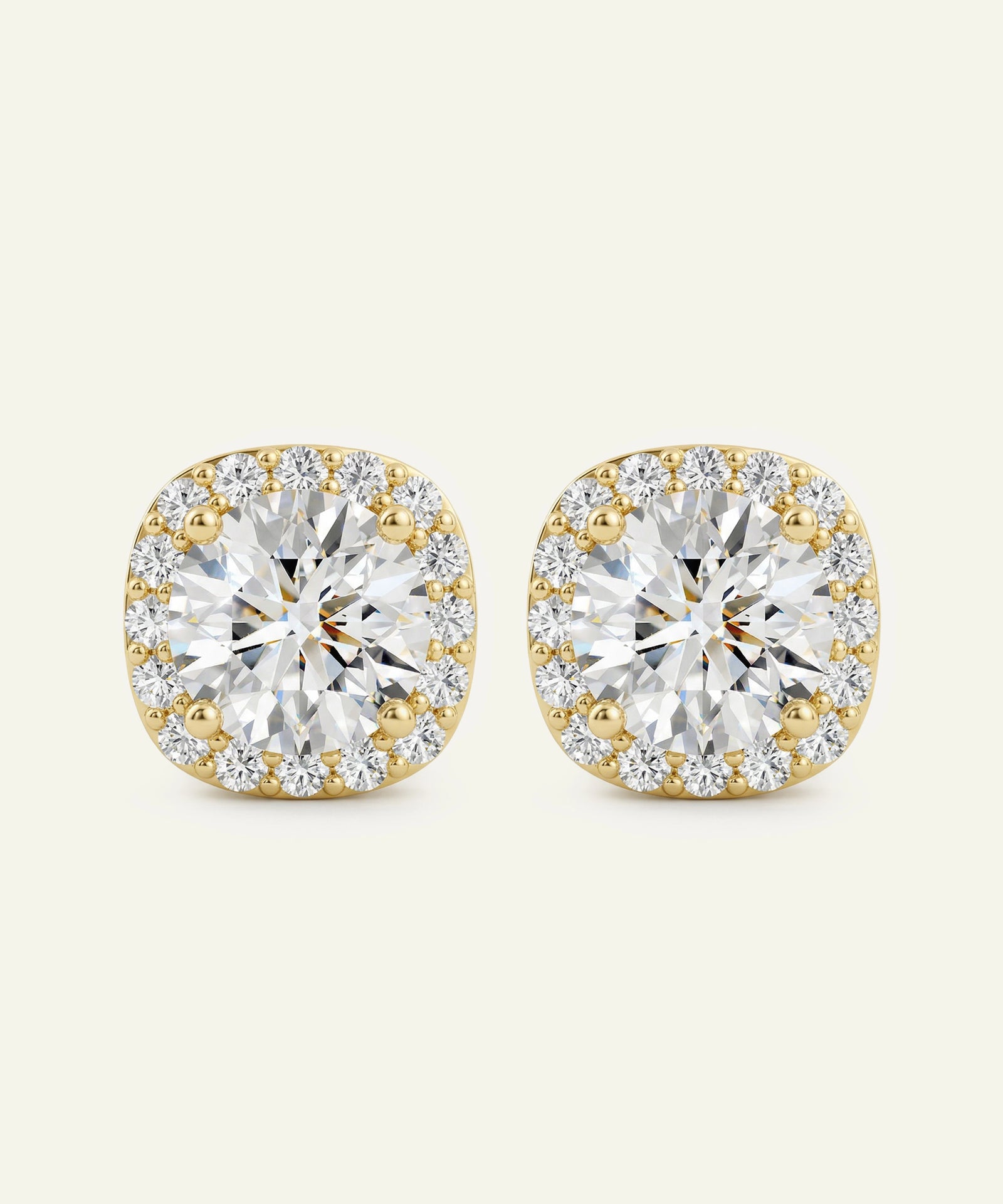Gold and diamond earrings on a beige background