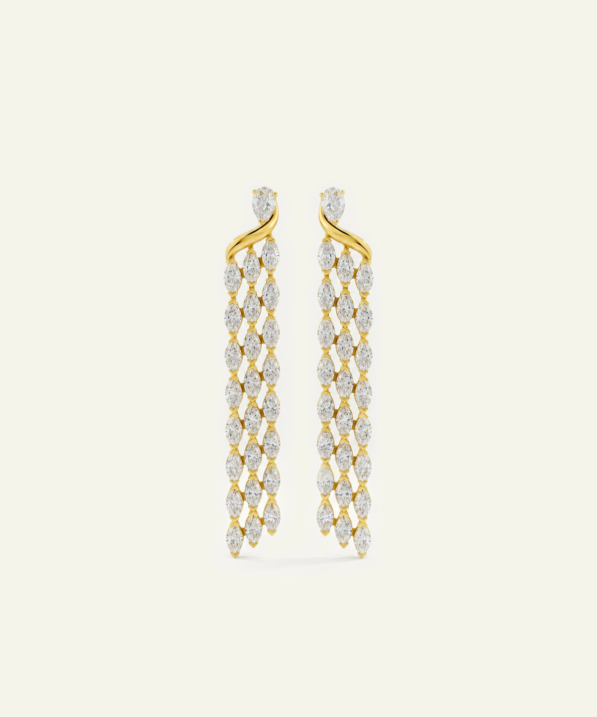 A pair of gold dangle earrings set with marquise-cut clear stones in a braided, cascading design, shown on a light cream background.